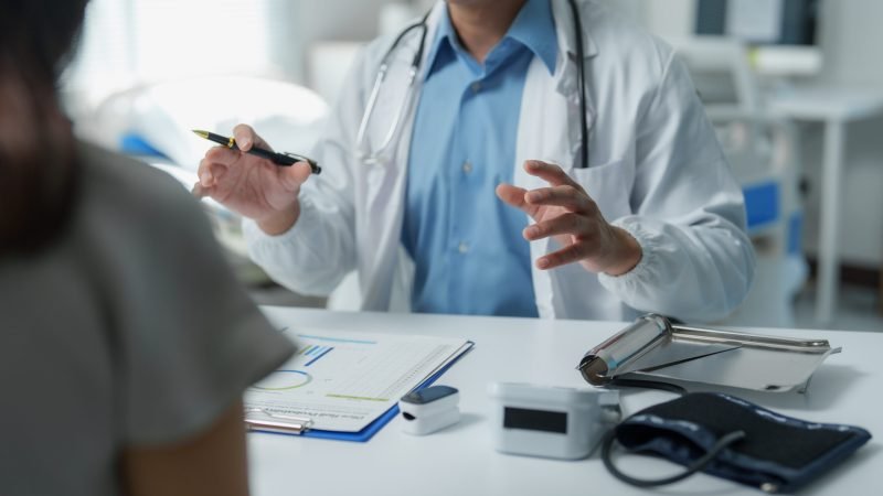 Doctor discussing a medical chart with a patient, clarifying the diagnosis and outlining the treatment plan in a hospital room filled with essential medical equipment